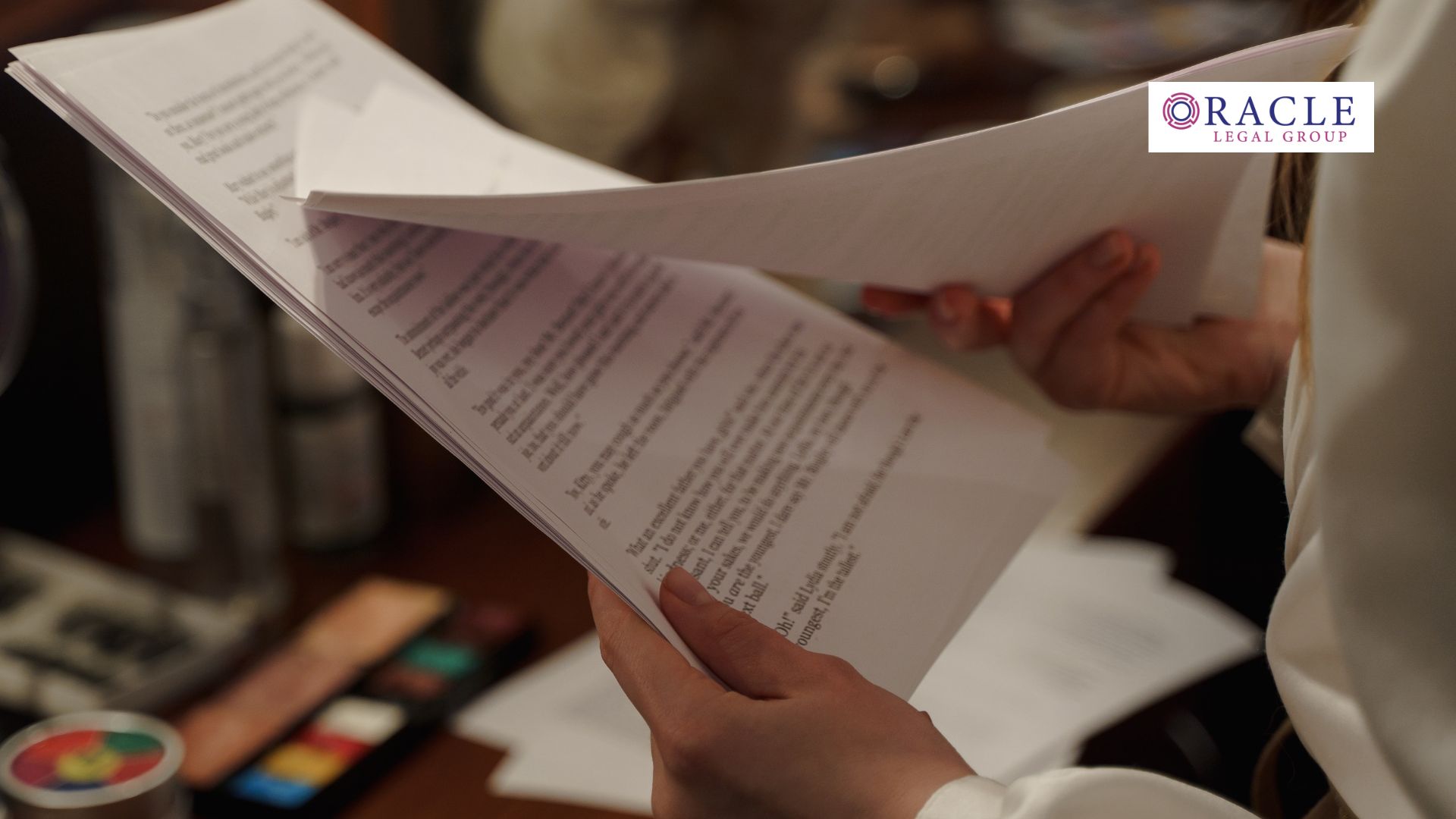 A close-up of a professional reviewing printed legal documents with detailed text; Oracle Legal Group logo appears in the corner