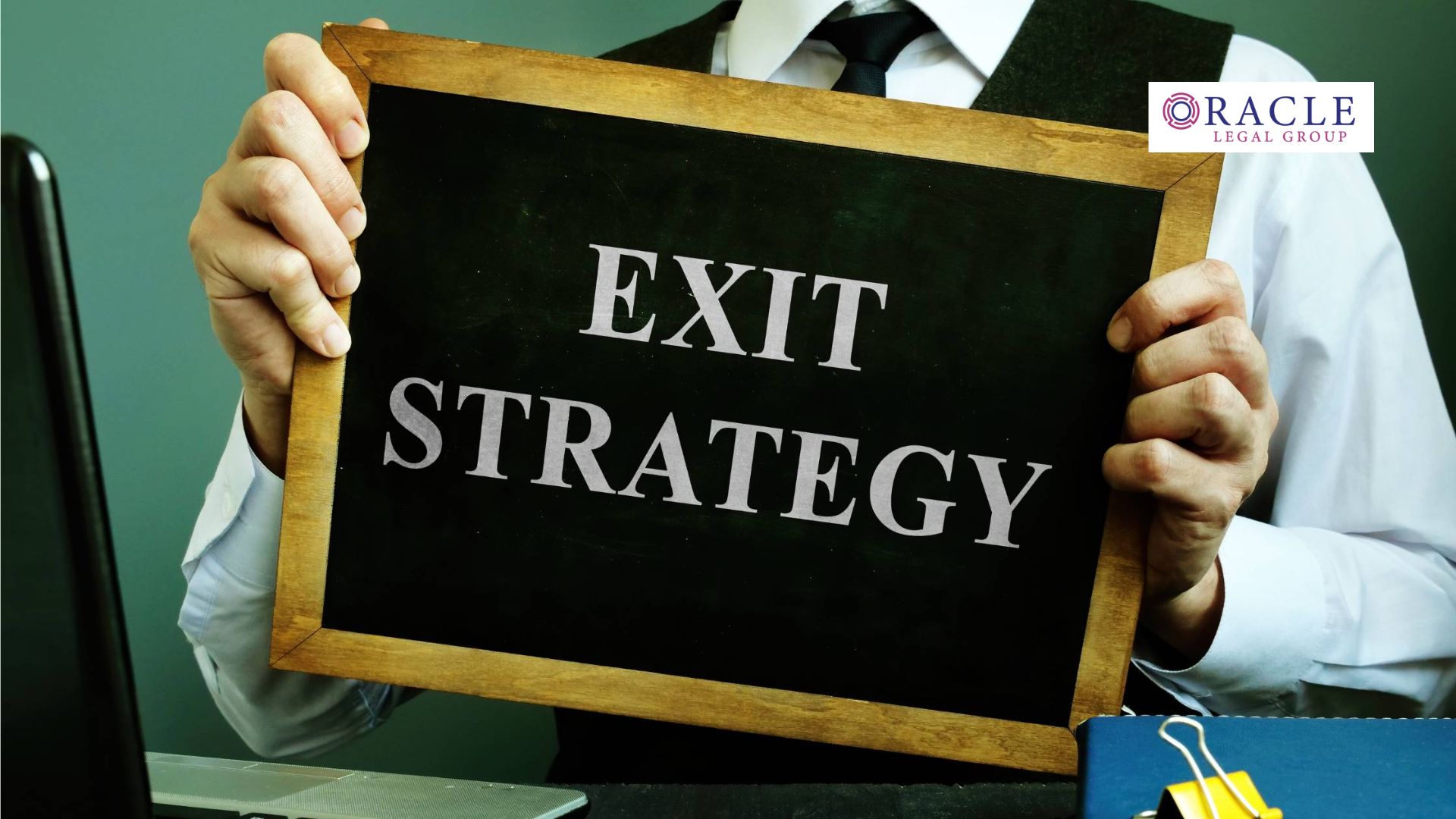 Business professional holding a chalkboard sign with the words "EXIT STRATEGY" in bold letters, representing business succession planning or exit strategies in a legal context; Oracle Legal Group logo in upper right